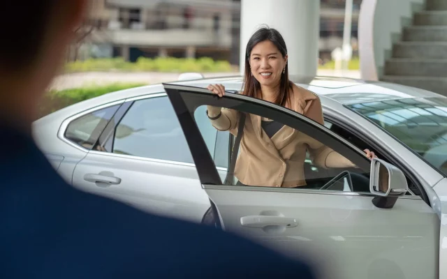 Backside of Receptionist welcoming the asian customer woman to v Backside of Receptionist welcoming the asian customer woman to visit maintainance service center for checking the car in showroom