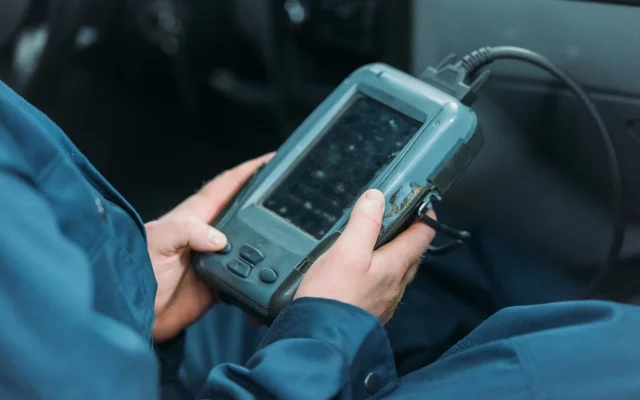Cropped shot of automechanic using a car diagnostic tool in a service workshop.
