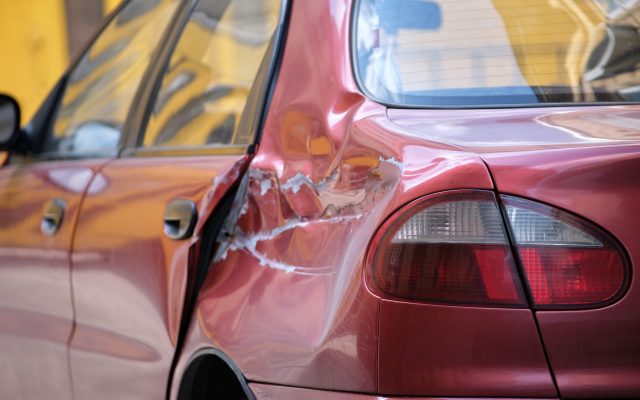 Dented car with damaged body parked on city street side. Road safety and vehicle insurance concept Dented car with damaged body parked on city street side. Road safety and vehicle insurance concept